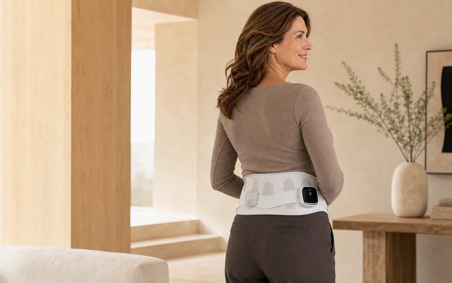 Woman wearing the ESCOSY Lumbar One wrap in a warm modern interior